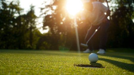 Blurred golfer playing golf in the evening golf course, on sun set evening time. Man playing golf on a golf course in the sun.の写真素材