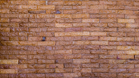 Background of stone wall texture photo, yellow stone wall background in horizontal pattern for home or resident decorationの写真素材