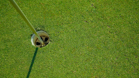 Top view. Golf hole on a green grass in the evening golf course with sunshine background.の写真素材