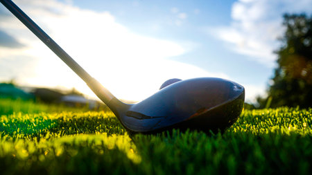 Golf clubs and golf balls on a green lawn in a beautiful golf course with morning sunshine. Close up of golf equipment on green grass.の写真素材