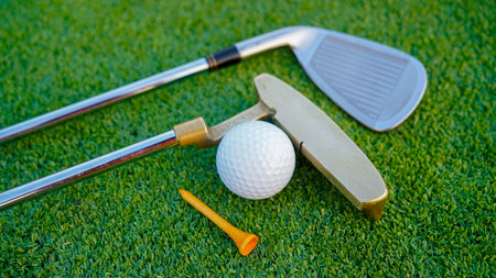 Golf clubs and golf balls on a green lawn in a beautiful golf course with morning sunshine. Close up of golf equipment on green grass.の写真素材