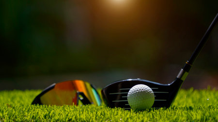 Golf clubs and golf ball on a green lawn in a beautiful golf course with morning sunshine. Close up of golf equipment on green grass.の写真素材
