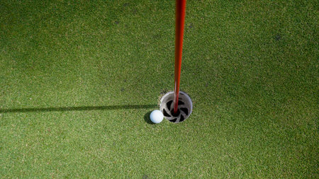 Golf ball is on a green lawn in a beautiful golf course with morning sunshine. Ready for golf in the first short.の写真素材