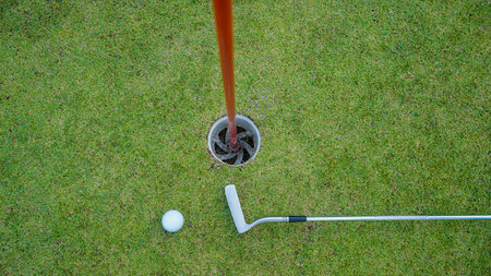Golf clubs and golf balls on a green lawn in a beautiful golf course with morning sunshine. Close up...