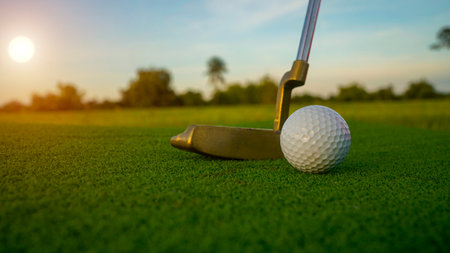 Golf clubs and balls on a green lawn in a beautiful golf course with morning sunshine. Close up of golf equipment on green grass.の写真素材