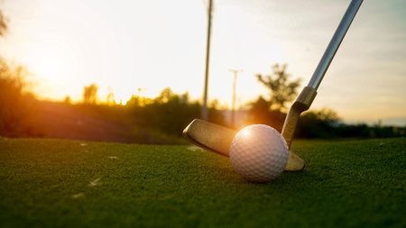 Golf clubs and balls on a green lawn in a beautiful golf course with morning sunshine. Close up of golf equipment on green grass.の写真素材