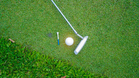 Golf clubs and golf balls on a green lawn in a beautiful golf course with morning sunshine. Close up...