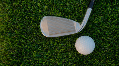 Golf grove and golf balls on a green lawn in a beautiful golf course with morning sunshine. Close up of golf equipment on green grass.の写真素材