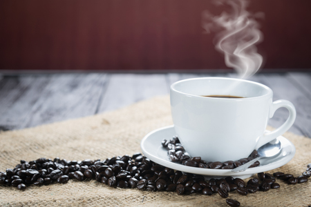 Coffee cup and beans on a rustic background. Coffee Espresso and a curl. Cup Of Coffee and coffee beans on tableの写真素材