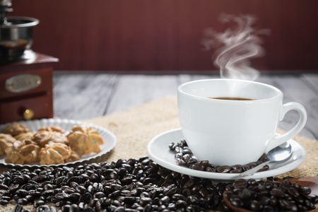 Coffee cup and beans on a rustic background. Coffee Espresso and a curl. Cup Of Coffee and coffee beans on tableの写真素材