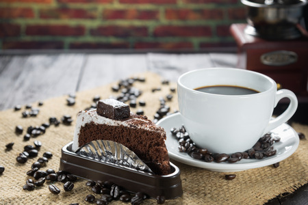 Coffee cup and beans on a rustic background. Coffee Espresso and a piece of cake with a curl. Cup Of Coffee and coffee beans on tableの写真素材