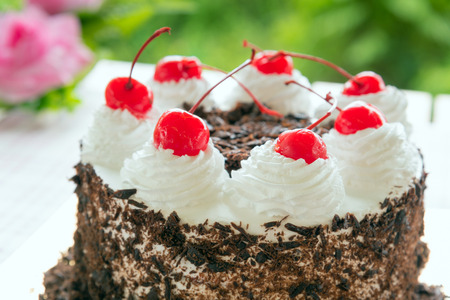 Black forest cake decorated with whipped cream and cherries