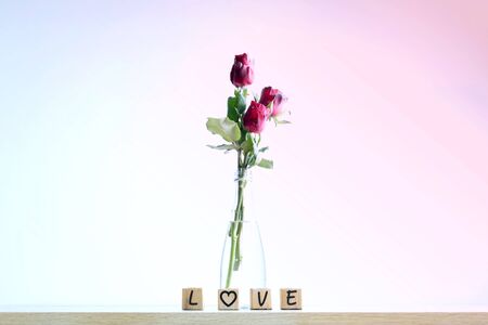 Four rustic alphabet blocks spelling out "Love" with a heart and red rose  on woodの写真素材