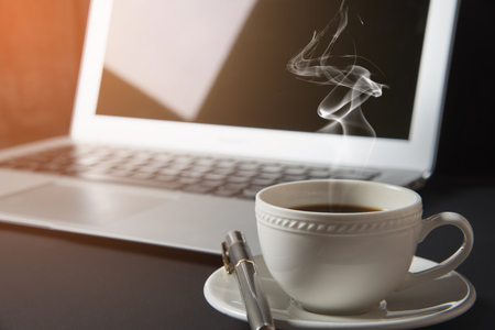 cup of coffee and laptop on the tableの写真素材