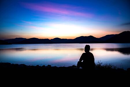 Silhouette of obese men on the lagoon looking at sunrise.の写真素材