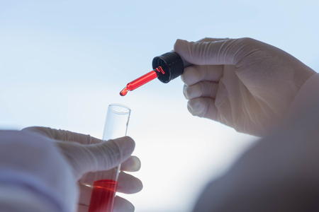 Chemist hand holding a medical dropper filled with blur backgroundの写真素材