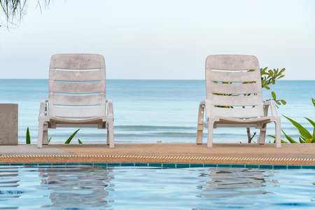 tropical swimming pool lounge chairs on the beach. Beautiful view of Swimming Pool with the sea at sunlight.のeditorial素材