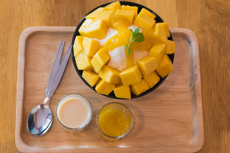 Bingsu ( Korea food) mango served with sweetened condensed milk on table, Mango Bingsu Korea dessert poured mango sauce.の写真素材
