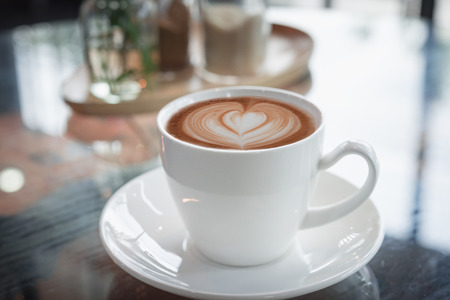 Hot art Latte Coffee in a cup on wooden table in Coffee shop の写真素材