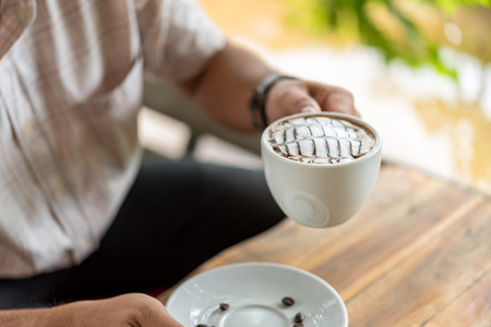 Guy holding a white coffee in a coffee shop