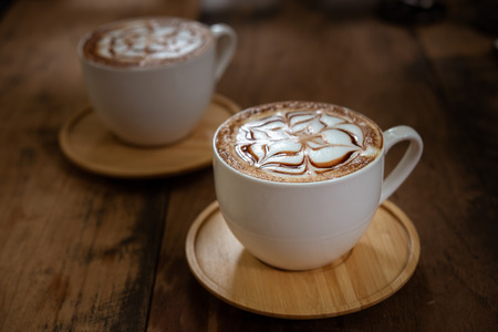 Two cups of coffee on black rustic background with beautiful latte art. Cup of coffee on a wooden tableの写真素材
