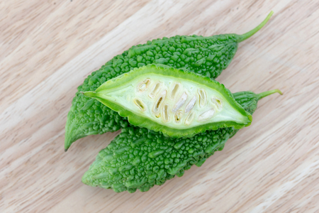 Bitter melon or Bitter gourd with half sliced on wooden background. bitter gourds.の写真素材