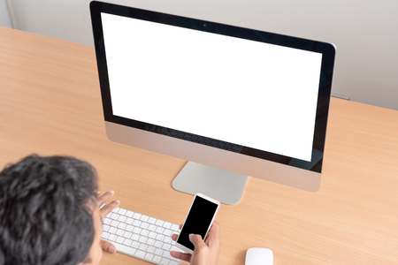 Office monitor computer, mouse on wooden table. computer and keyboard, mouse with blank screen. Digital business concept. Young man looking at empty computer screen, back viewの写真素材