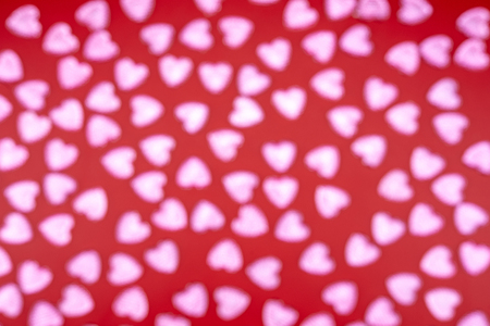 Background bokeh in the form of hearts of red and pink color. Pink hearts on red background. Top...