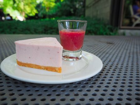 Slice of plain cheesecake with cranberry sauce on white plateの写真素材
