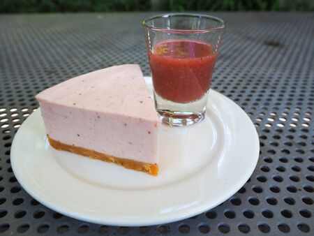 Piece of cheesecake. Slice of plain cheesecake with cranberry sauce on white plate decorated. Closeup viewの写真素材