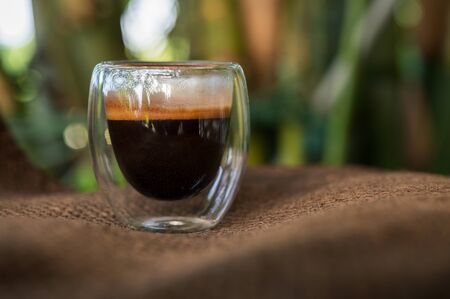 Cup of espresso on the table. glass beaker for shot-cocktail or coffee drinks. Close up of a glass of espresso. Hot coffee in a glass with double walls isolated on a white background.の写真素材