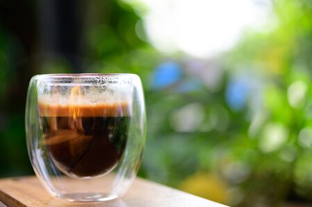 Cup of espresso on the table. glass beaker for shot-cocktail or coffee drinks. Close up of a glass of espresso. Hot coffee in a glass with double walls isolated on a white background.の写真素材