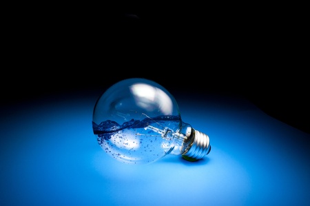 energy concept, water inside the light bulb on blue floor in darkの写真素材
