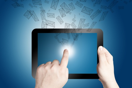 Hand holding and pointing on touch screen digital tablet with 3D mail icon coming from the screen on blue backgroundの写真素材