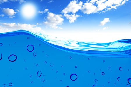 Air bubbles in ocean water rise to the surface with cloudy sky with sun in the backgroundの写真素材