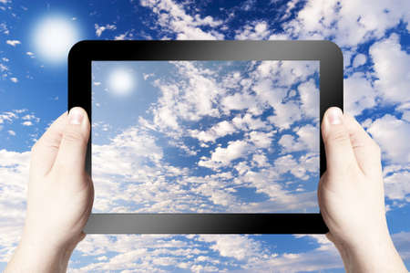 Hands holding on digital tablet with Cloudy sky backgroundの写真素材