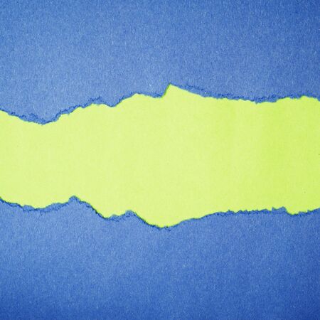 Torn blue color paper on green color background with space for text の写真素材