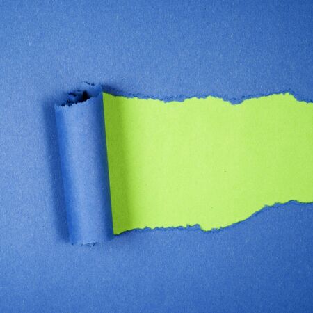 Torn blue color paper on green color background with space for text の写真素材