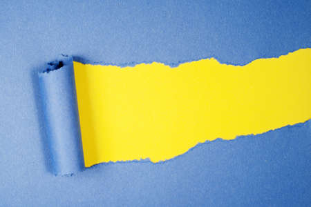 Torn blue color paper on yellow color background with space for text の写真素材