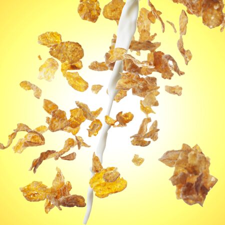 Breakfast Corn flakes wit milk splash on yellow backgroundの写真素材