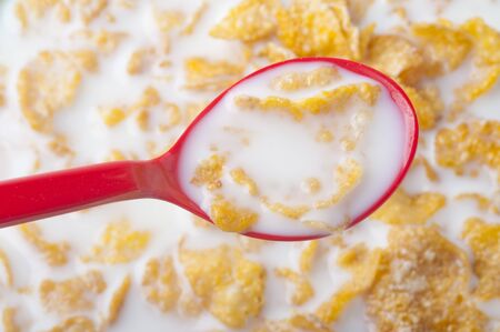 Close up on red spoon dipping into corn flakesの写真素材