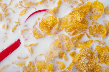 Close up on red spoon dipping into corn flakesの写真素材