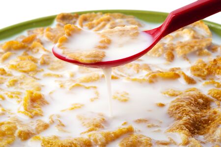Close up on red spoon dipping into corn flakesの写真素材