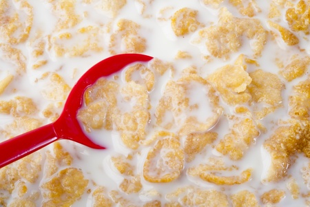 Close up on red spoon dipping into corn flakesの写真素材