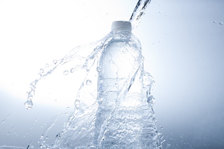 bottle of water and water splash isolated on blue backgroundの写真素材
