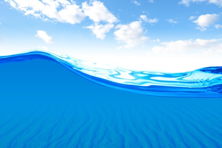 Air bubbles in ocean water rise to the surface with cloudy sky with sun in the backgroundの写真素材