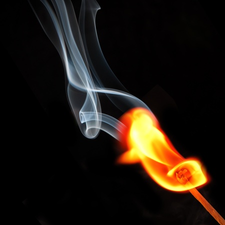 Spark of match with fire and smoke on black background