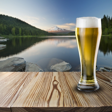 Glass of beer on wood with mountain viewの写真素材
