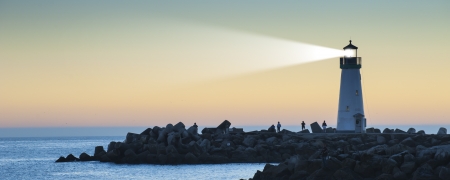 Lighthouse with light beam on ocean
