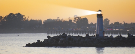 Lighthouse with light beam on oceanの写真素材